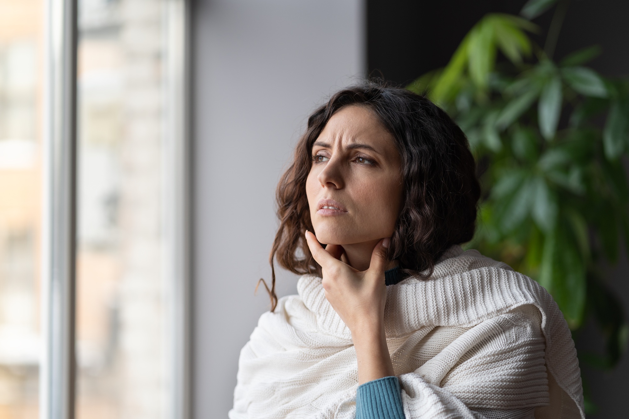 Upset sick woman standing at home touching swollen neck glands, having sore throat from virus