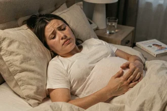 Femme enceinte au troisième trimestre allongée dans son lit, les yeux ouverts, souffrant de troubles du sommeil