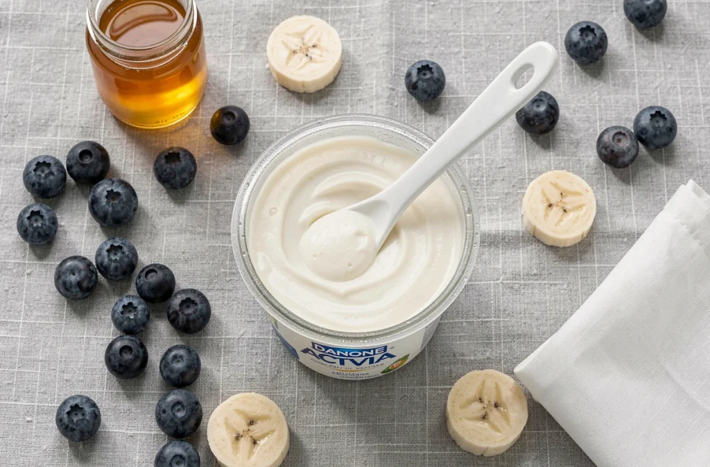 Présentation soignée d'un yaourt Activia avec des fruits frais pour illustrer une consommation quotidienne équilibrée